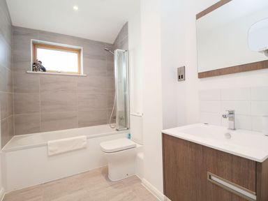 A bathroom with a bathtub shower combo toilet and sink with a mirror at Woodbridge Penthouse in Woodbridge