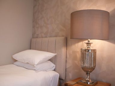 A bed with two pillows and a table lamp on a wooden nightstand at Woodbridge Penthouse in Woodbridge