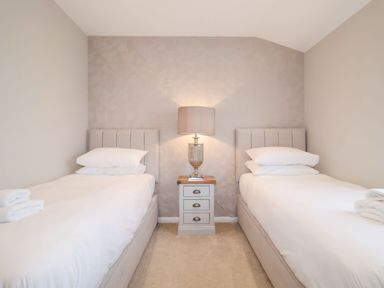 A bedroom with two single beds separated by a bedside table with a lamp at Woodbridge Penthouse in Woodbridge