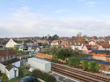 A view of a railway track with houses and trees in the background at Woodbridge Penthouse in Woodbridge