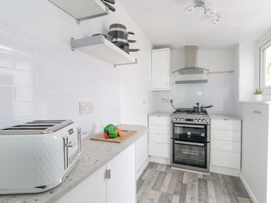 A kitchen with a toaster and chopping board with vegetables on the counter at Day Cottage in Weymouth