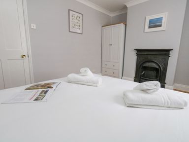 A bedroom with a bed with towels and a magazine a wardrobe a fireplace and framed pictures at Day Cottage in Weymouth