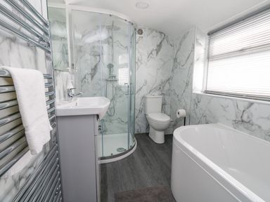 A bathroom with a shower enclosure sink toilet bathtub heated towel rail and a window with blinds at Day Cottage in Weymouth
