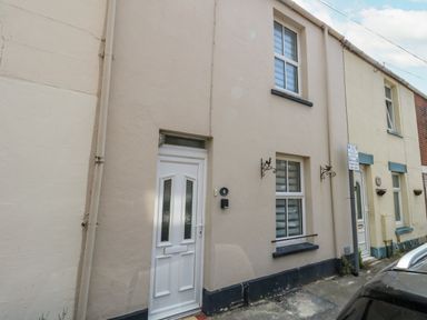 The exterior of a beige terraced house with white door and two windows at Day Cottage in Weymouth