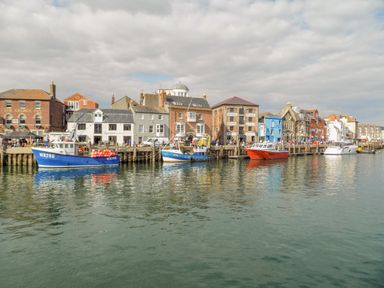 A harbor with boats docked beside buildings along the waterfront at Day Cottage in Weymouth