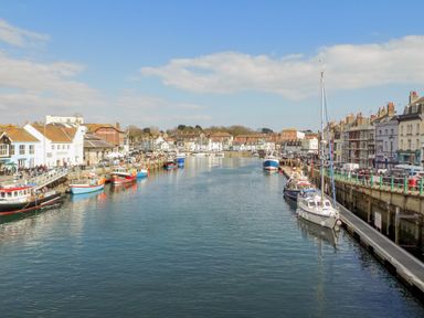 A harbor with boats docked along both sides and buildings lining the waterfront at Day Cottage in Weymouth