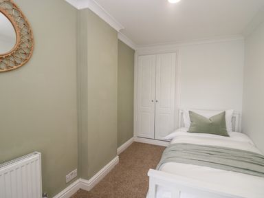 A small bedroom with a single bed pillow and blanket and a built in wardrobe at Wainwright Cottage in Gosforth