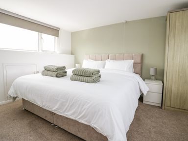 A bedroom with a bed towels on it a bedside table with a lamp and a wardrobe at Wainwright Cottage in Gosforth