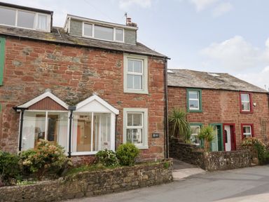 Stone cottages with small front gardens and windows on a street at Wainwright Cottage in Gosforth