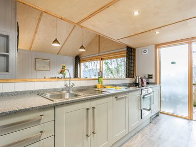 A kitchen counter with a sink kettle oven and a frosted glass door at Lodge 3 in Corfe Castle