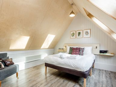 A bedroom with a double bed wooden floors skylight and an armchair at Lodge 11 in Corfe Castle
