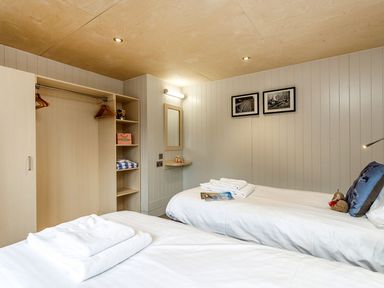A bedroom with two single beds white towels open wardrobe and black and white pictures on wall at Lodge 12 in Corfe Castle