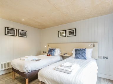 A bedroom with two single beds and framed pictures on the wall at Lodge 13 in Corfe Castle