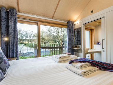 A bedroom with a view of trees and a river at Lodge 15 in Corfe Castle