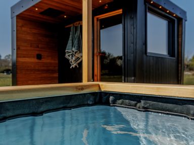 A hot tub with wooden decking and a building in the background at Lodge 15 Corfe Castle