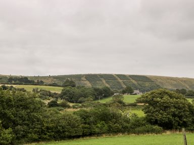A rural landscape with green fields trees and a house at Lodge 16 Corfe Castle