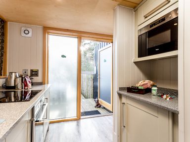A kitchen with appliances and a door to the garden at Lodge 16 Corfe Castle
