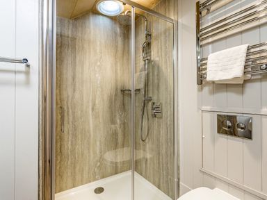 A shower with glass door and towel rack at Lodge 16 Corfe Castle
