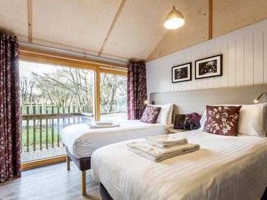A bedroom with two beds and windows at Lodge 17 in Corfe Castle