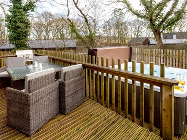 An outdoor deck with a table and hot tub at Lodge 17 in Corfe Castle