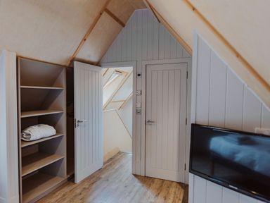 A bedroom with shelves and a television at Lodge 19 in Corfe Castle