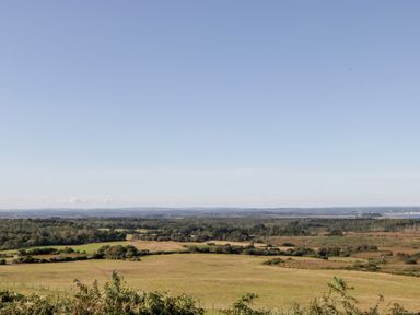 A landscape view of fields trees and distant hills under a clear sky at Lodge 22 in Corfe Castle