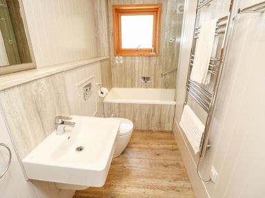 A bathroom with a sink toilet bathtub window and towel racks at Lodge 22 in Corfe Castle