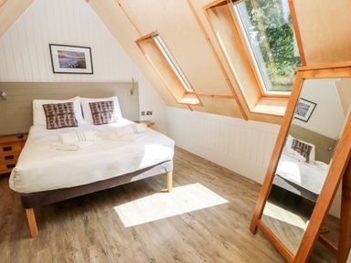 A bedroom with a double bed two skylight windows and a full length mirror at Lodge 22 in Corfe Castle