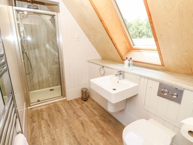 A bathroom with a shower stall sink toilet and a slanted window at Lodge 22 in Corfe Castle