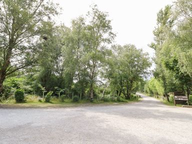 A gravel path surrounded by trees and greenery with an exit sign on the right at Lodge 22 Corfe Castle