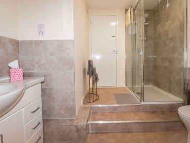 A bathroom with a sink vanity a shower cubicle and towel rack at Falcon House in Tintagel