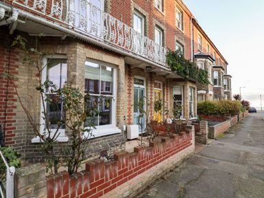 A row of brick terrace houses with small front gardens and decorative railings at Elkhorn in Southwold