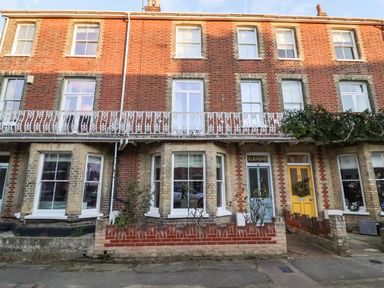A row of brick townhouses with bay windows and a blue door with a sign reading Elkhorn in Southwold