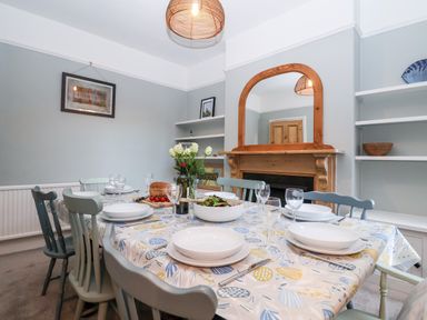 A dining room with a set table and a wooden framed mirror above a fireplace at Elkhorn in Southwold