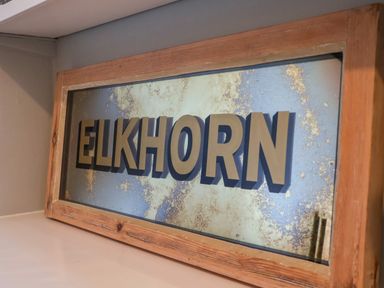 A framed mirror with the word ELKHORN in raised letters inside a room at Elkhorn in Southwold