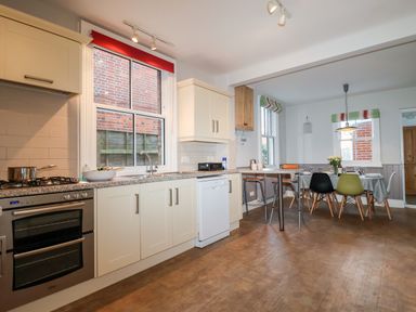 A kitchen with white cabinets and a dining table with chairs at Elkhorn in Southwold
