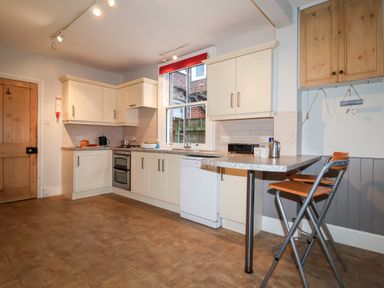 A kitchen with cream cabinets a wooden door tiled floor and two stools at Elkhorn in Southwold