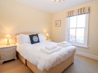 A bedroom with a double bed bedside tables lamps window and towels on the bed at Elkhorn in Southwold