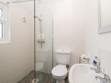 A bathroom with a toilet sink shower and window at Elkhorn in Southwold