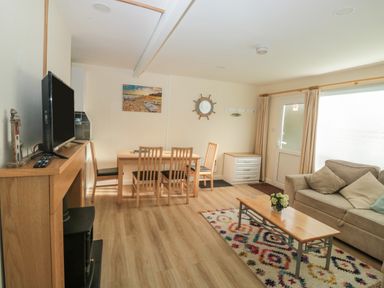 A living room with a sofa and coffee table and a dining table with chairs at The Bolthole in Dartmouth