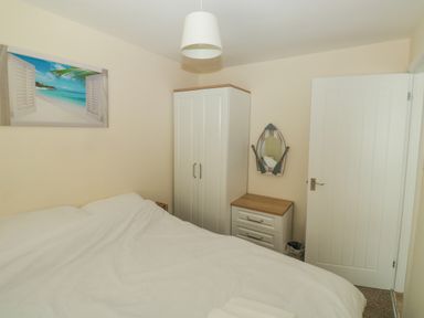 A bedroom with a bed white wardrobe a chest of drawers and a mirror at The Bolthole in Dartmouth
