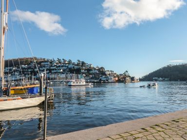 A harbor with boats on water and houses on hills in the background at The Bolthole in Dartmouth