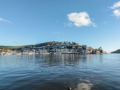 A waterfront view of a hillside town with boats docked in the harbor at The Bolthole in Dartmouth