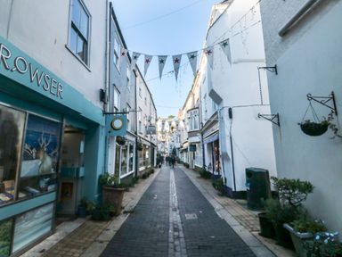 A narrow pedestrian street with shops on both sides and bunting overhead at The Bolthole in Dartmouth