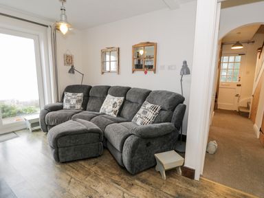 A living room with a gray sectional sofa pillows two wall mirrors and a floor lamp at Sibrwd Y Mor in Harlech