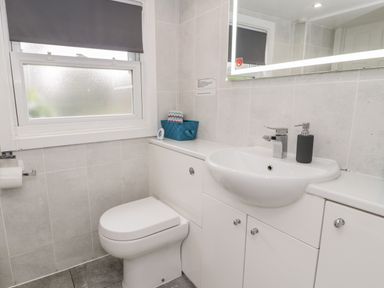 A bathroom with a toilet sink mirror window and a black soap dispenser at Sibrwd Y Mor in Harlech