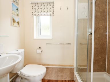 A bathroom with a sink toilet shower and a window at 11 The Dell in Mundesley