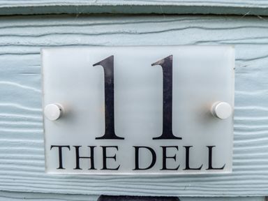A house number sign with 11 and the name The Dell on a textured light blue wall at 11 The Dell in Mundesley
