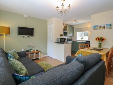 A living room with a television and dining area at 14 The Dell Mundesley