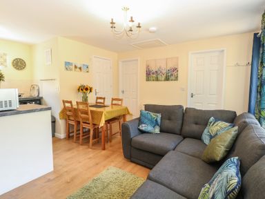 A living room with a sofa and dining area at 14 The Dell Mundesley